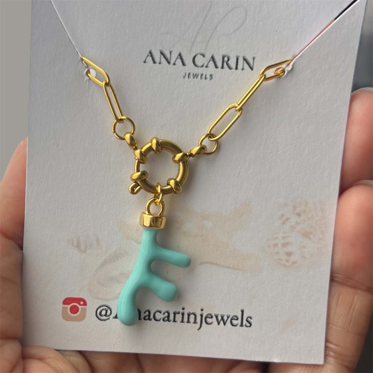 Collar de acero inoxidable sostenible con colgante azul, en base dorada, presentado en bolsa de joyería.